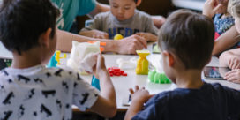 Children sit at a makerspace table and create things with art and science to demonstrate the importance of makerspaces.